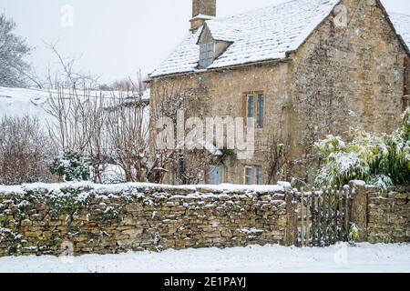 Cotswold cottage in pietra e fienile nella neve di dicembre. Taynton, Cotswolds, Oxfordshire, Inghilterra Foto Stock