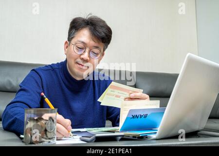 L'uomo asiatico di mezza età si prepara alla dichiarazione dei redditi. Foto Stock