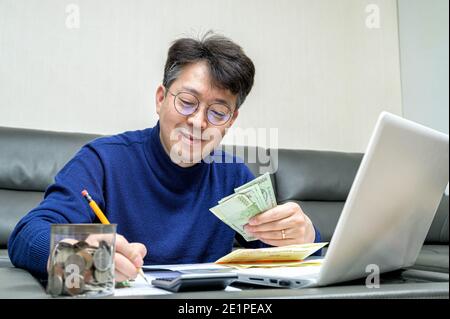 L'uomo asiatico di mezza età si prepara alla dichiarazione dei redditi. Foto Stock