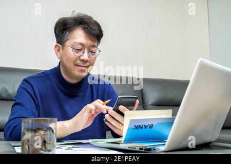 L'uomo asiatico di mezza età si prepara alla dichiarazione dei redditi. Foto Stock