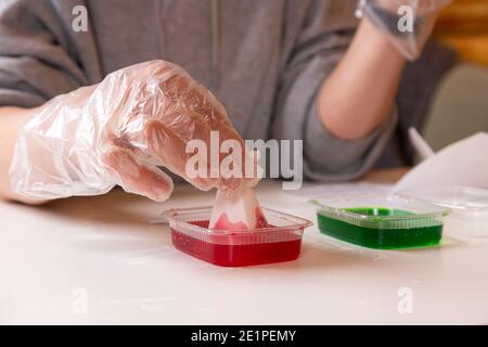 Concetto di educazione e formazione chimica. Primo piano di una donna che immergi un cono in una soluzione in un connettore per indurre una reazione chimica e crescere Foto Stock