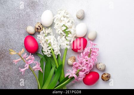 Brillante composizione pasquale con quaglia, uova di pasqua, giacinto rosa e bianco su fondo di pietra. Disposizione piatta, vista dall'alto. Concetto di Pasqua - immagine Foto Stock