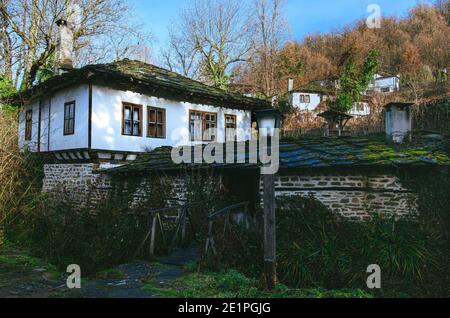 Tradizionale casa bulgara in revival villaggio di Bozhentsi durante l'inverno con muschio sul tetto di pietra. Foto Stock
