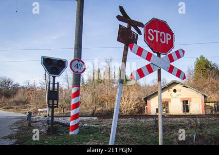 Vecchio segnale di avvertimento arrugginito e nuovo segnale di stop all'attraversamento a livello del treno senza equipaggio in Bulgaria Foto Stock