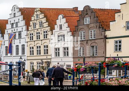 FRIEDRICHSTADT, GERMANIA-13 LUGLIO 2019: Mercato con una fila di case storiche a timpano sulla piazza del mercato di Friedrichstadt, Germania Foto Stock