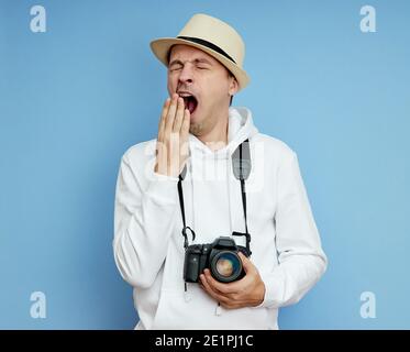 L'uomo con la macchina fotografica è stanco e sbadiglia Foto Stock