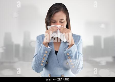 Sensazione di bruciore al naso di una donna d'affari a causa del fumo tossico e del particolato presente nell'aria. Donna con allergia, tenendo un tessuto sul naso. P. Foto Stock