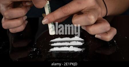Donna tossicodipendente russare cocaina in polvere con banconota da dollaro arrotolata. Concetto di stupefacenti. Primo piano della macro. Scatto panoramico. Banner panorama. Alta r Foto Stock