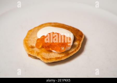 Singolo salmone Rosso Caviar Blini con crema acida su A. Piastra bianca Foto Stock