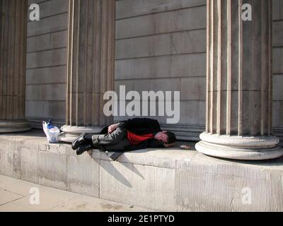 Uomo che dorme sotto i pilastri della Bank of England Threadneedle Street, City of London Foto Stock