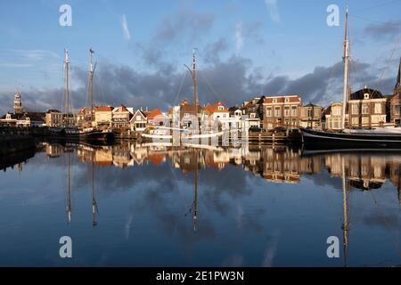 Grandi barche a vela e yacht da diporto si specchiano in acque blu con il tramonto nel porto di Lemmer a Friesland, Paesi Bassi Foto Stock