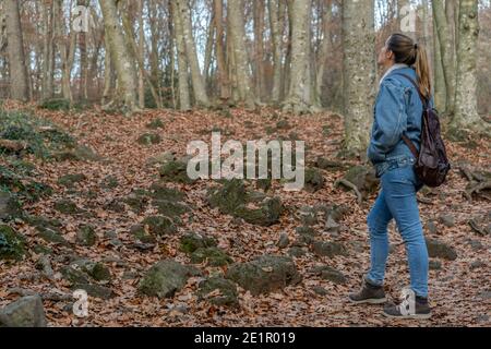 Giovane donna che guarda la foresta e cammina in un paesaggio autunnale stupefacente.Copia spazio per il testo. Foto Stock