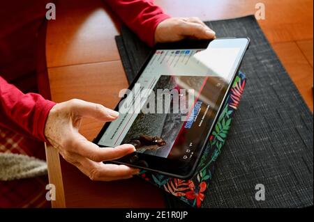 Primo piano di una donna anziana che legge le ultime notizie su Coronavirus Pandemic sul suo iPad Apple. Foto Stock