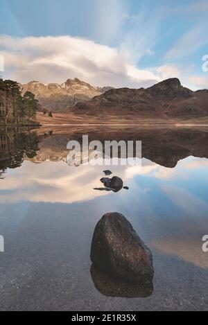 Bella alba invernale su Blea Tarn nel Lake District con Pikes Langdale innevate in lontananza Foto Stock