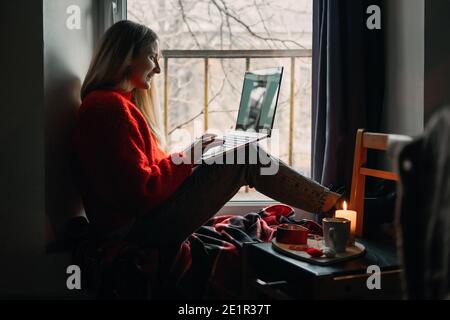 Donna che usa l'app online dating sul laptop. Giorno di San Valentino durante l'epidemia di Coronavirus. Amore a distanza, solitudine in auto-isolamento nel tempo di Foto Stock