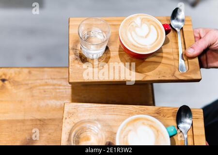 Due tazze di cappuccino su vassoi di legno. Concetto di caffè e cameriere Foto Stock