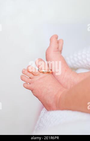 Anello di nozze sul pollice delle gambe dei bambini piccoli sopra sfondo bianco Foto Stock