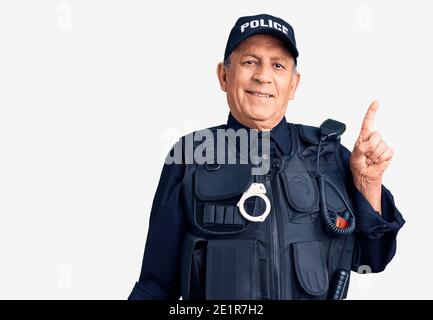 Uomo anziano bello che indossa uniforme della polizia sorridente felice indicando con mano e dito di lato Foto Stock