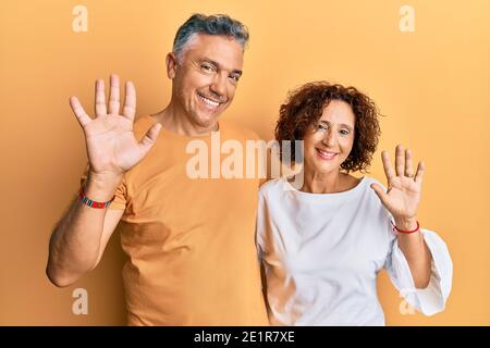 Bella coppia di mezza età insieme indossare abiti casual cintura dicendo ciao felice e sorridente, amichevole gesto di benvenuto Foto Stock