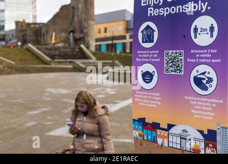 REGNO UNITO. 8 gennaio 2021. Una signora passa oltre il poster delle misure di sicurezza COVID19 in Galles. Il nuovo ceppo altamente contagioso del virus ha preso una posizione di rilievo in Galles. Un test su quattro torna positivo. La restrizione di livello quattro è serrata e il blocco continuerà fino al 29 gennaio. Credit: SOPA Images Limited/Alamy Live News Foto Stock