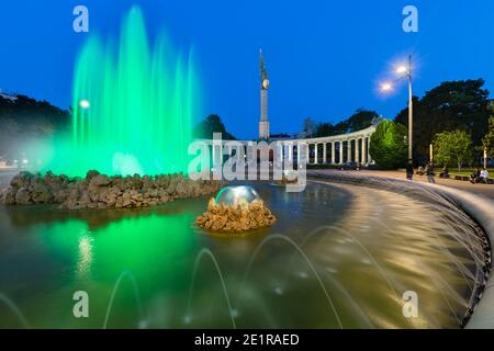 Vista notturna della colorata fontana di Schwarzenbergplatzin Vienna, Austria con sullo sfondo il Memoriale della guerra sovietica. Foto Stock