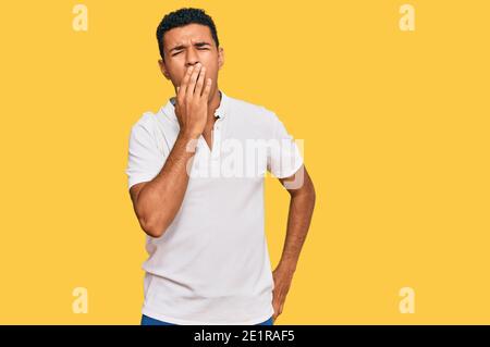 Giovane arabo che indossa abiti casual annoiato tendente stanco coprendo la bocca con la mano. Riposante e sonnolenza. Foto Stock