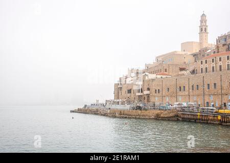 Old Jaffa Port e Tel-Aviv in tempo di nebbia. Antiche case in pietra che si affacciano sul Mar Mediterraneo. Foto di alta qualità Foto Stock