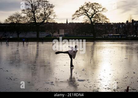 Edimburgo, Scozia, Regno Unito. 9 gennaio 2021. I membri del pubblico pattinare e camminare sul laghetto congelato in Inverleith Park a Edimburgo oggi. In città persistono temperature quasi gelide e nonostante un grave blocco Covid-19 il parco era pieno di persone che camminavano e si esercitavano. Iain Masterton/Alamy Live News Foto Stock