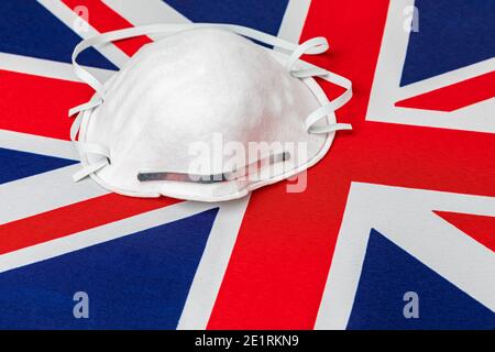 Bandiera del Regno Unito e maschera facciale N95. Concetto di Covid-19 coronavirus blocco, aumento, divieto di viaggio e crisi sanitaria Foto Stock