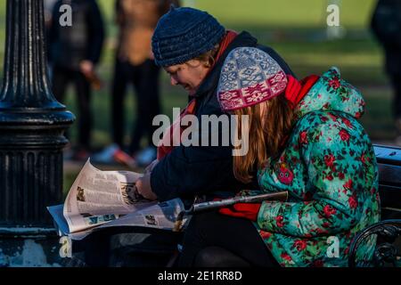 Londra, Regno Unito. 9 gennaio 2021. Il messaggio chiaramente non sta attraversando come la zona intorno al bandstand è occupato con le persone che si riunono / seduto / bere - in questo caso i lettori di giornali ignorare l'avviso sul retro del giornale - vita all'aperto su Clapham comune in Lockdown 3 che sostituisce il livello 4 e comprende un soggiorno Istruzioni a casa per allentare la pressione sul sistema NHS. Credit: Guy Bell/Alamy Live News Foto Stock