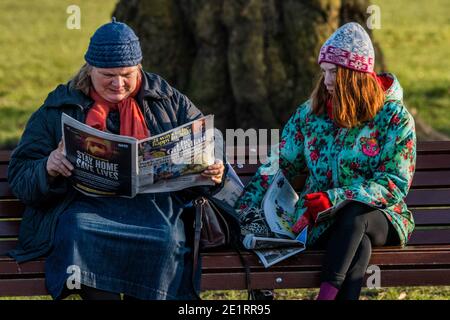 Londra, Regno Unito. 9 gennaio 2021. Il messaggio chiaramente non sta attraversando come la zona intorno al bandstand è occupato con le persone che si riunono / seduto / bere - in questo caso i lettori di giornali ignorare l'avviso sul retro del giornale - vita all'aperto su Clapham comune in Lockdown 3 che sostituisce il livello 4 e comprende un soggiorno Istruzioni a casa per allentare la pressione sul sistema NHS. Credit: Guy Bell/Alamy Live News Foto Stock