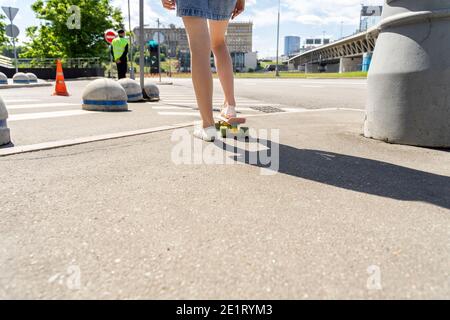 ragazza in una gonna corta su uno skateboard primo piano in di fronte a un incrocio Foto Stock