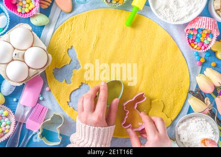 Famiglia fatta in casa vacanza pasta di Pasqua concetto. Pasqua cottura sfondo con la mamma e la figlia bambino mani, piano vista dall'alto. Con l'impasto, si forma la cupcake Foto Stock