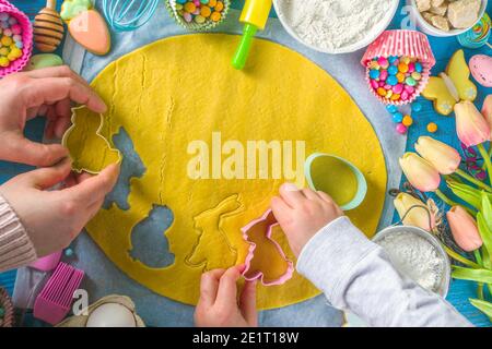 Famiglia fatta in casa vacanza pasta di Pasqua concetto. Pasqua cottura sfondo con la mamma e la figlia bambino mani, piano vista dall'alto. Con l'impasto, si forma la cupcake Foto Stock