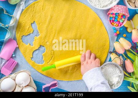 Famiglia fatta in casa vacanza pasta di Pasqua concetto. Pasqua cottura sfondo con la mamma e la figlia bambino mani, piano vista dall'alto. Con l'impasto, si forma la cupcake Foto Stock