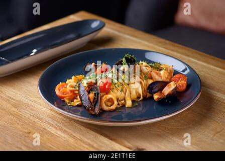 Pappardelle con frutti di mare, cozze e pomodori sul tavolo al ristorante, menu concetto di cibo. Cucina italiana Foto Stock