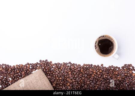 Vista dall'alto della tazza bianca con caffè caldo sfondo di frusta e con fagioli di caffè Foto Stock