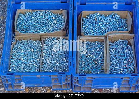 Molte parti di dadi e bulloni in casse blu Foto Stock