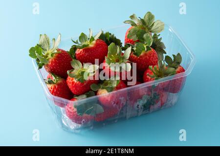 Fragole in confezione di plastica su sfondo blu Foto Stock