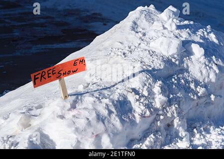 Rimozione della neve con un divertente segno che dà via la neve libera Foto Stock
