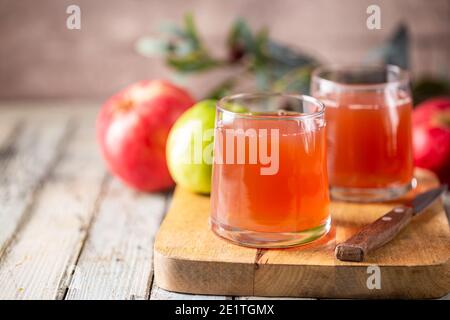 Bicchiere di succo di mela fresco e mele rosse su legno sfondo Foto Stock