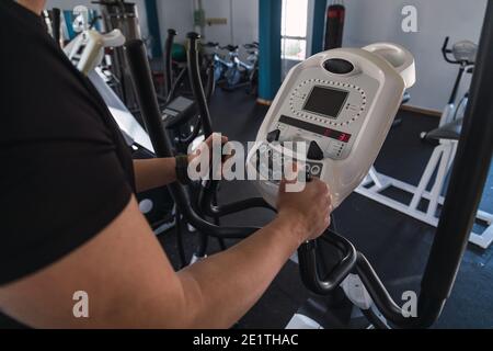 Uomo irriconoscibile mani su corrimano ellittico dell'addestratore nel randello di sport. Cardio allenamento sfondo, in esecuzione su tapis roulant. Stile di vita sano, ragazzo traini Foto Stock