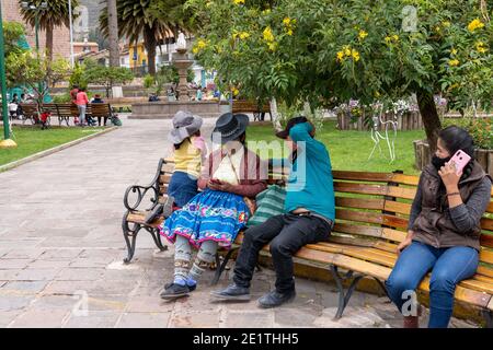 Le donne locali e l'uomo controllano i loro telefoni cellulari a Urubamba nel distretto di Cusco, Perù Foto Stock