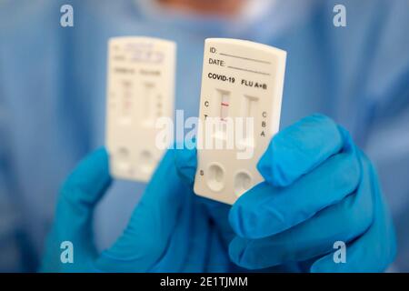 Il test rapido positivo COVID-19 è visto nella mano di un operatore medico che indossa dispositivi di protezione individuale. Foto Stock