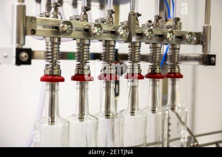Primo piano di una macchina automatica per il riempimento di bottiglie per uso industriale. Foto Stock