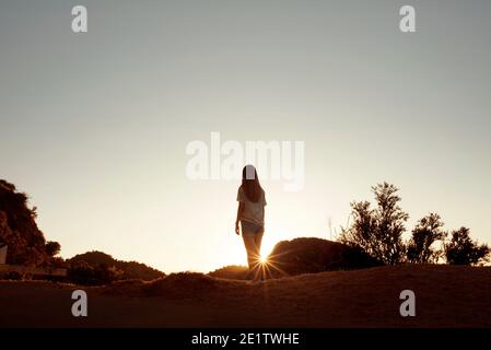 Silhouette di giovane ragazza da dietro guardando la vista durante il tramonto. The Hollywood Sign, Los Angeles, California, Stati Uniti. Ago 2019 Foto Stock