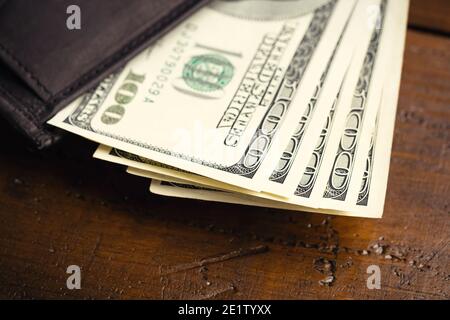 Portafoglio in pelle pieno di denaro su tavolo di legno - cento banconote USA con ritratto del presidente Franklin. Contanti di cento fatture del dollaro, valuta della carta Foto Stock