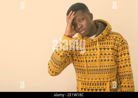 Studio shot del giovane nero africano avente mal di testa contro uno sfondo bianco Foto Stock