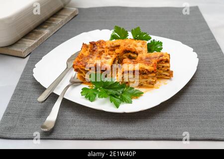 Lasagne di manzo servite con prezzemolo fresco primo piano su bianco piastra Foto Stock