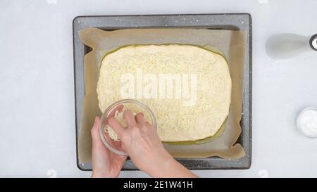 Pane piatto con mozzarella e ricetta graduale. L'impasto del pane si avvicina alla griglia da forno, vista dall'alto Foto Stock